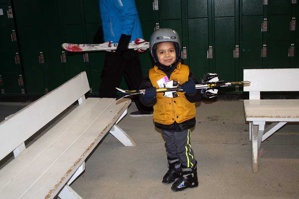Mount Peter instructor helping Elias clip into skis